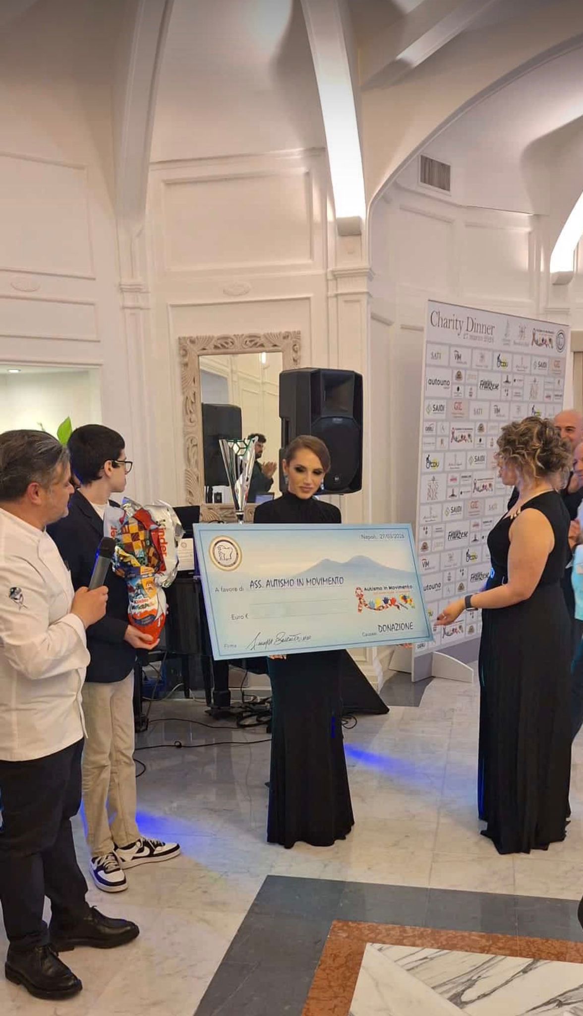 Dietro questo lavoro quotidiano c’è l’impegno instancabile della presidente Annalisa Vetrano, anima e punto di riferimento di “Autismo in Movimento”. Con discrezione, forza e una rara capacità di trasformare la fragilità in energia, da anni porta avanti un lavoro concreto accanto ai ragazzi e alle loro famiglie, non cerca riflettori, li accende sugli altri. È anche grazie alla sua tenacia se “Autismo in Movimento” è diventata, nel tempo, molto più di un’associazione: una casa, un luogo di ascolto, un presidio umano in cui nessuno si sente invisibile. La serata del Bertolini’s Hall porta anche la sua firma; la firma di una donna che ha scelto di non fermarsi alla sensibilità, ma di trasformarla in azione. In un’epoca in cui troppo spesso tutto viene misurato in numeri, visibilità e apparenza, “Autismo in Movimento” ricorda una verità semplice e scomoda: le persone non sono statistiche, sono storie, paure, sogni, fatiche e ogni famiglia che affronta il percorso dell’autismo ha diritto non soltanto a servizi e sostegno, ma anche a sentirsi parte di una comunità. Napoli, in questa occasione, ha risposto presente, senza retorica, senza passerelle, con quel calore autentico che appartiene alle città che sanno ancora emozionarsi davanti al bene. Perché la solidarietà vera non è quella che si fotografa, è quella che resta, il giorno dopo,è quella che costruisce progetti, tende la mano, crea futuro e il futuro, venerdì sera, aveva il volto di chi crede che nessuno debba sentirsi escluso, aveva il volto di tanti ragazzi, di tante famiglie, di tanti volontari; ma aveva anche un nome preciso: “Autismo in Movimento”. E una donna che, con ostinata dolcezza, continua ogni giorno a trasformare l’inclusione da parola a realtà: Annalisa Vetrano.